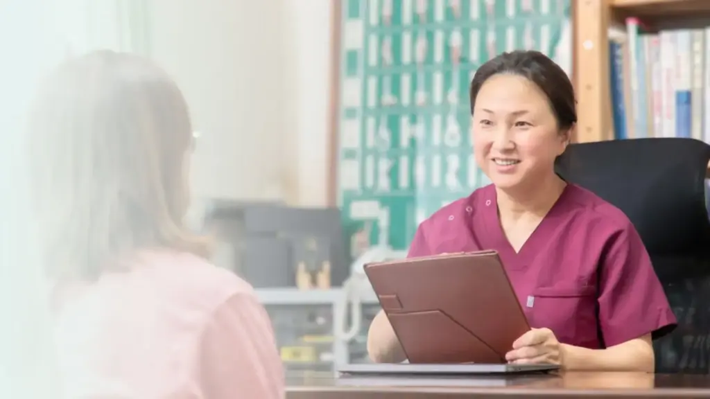 施術者が笑顔でカウンセリングを行っている様子。落ち着いた雰囲気の院内で相談を受けている。