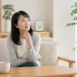 更年期の体の変化を感じながら、自然光の入る部屋で静かに座る40〜60代女性
