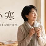 小寒の季節、冬の窓辺で温かいお茶を持つ女性と「寒さが深まる頃の養生」の文字