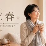 立春の文字と、窓辺で温かい飲み物を手に春の光を眺める女性。暦の上で春の始まりを表現した画像。