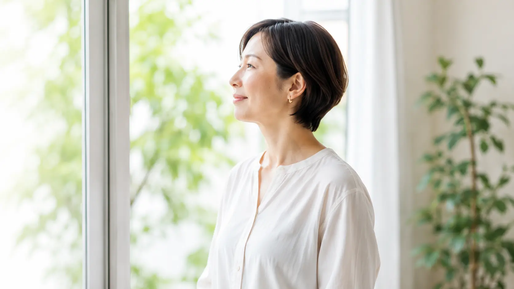 窓辺でやわらかな表情を見せる女性