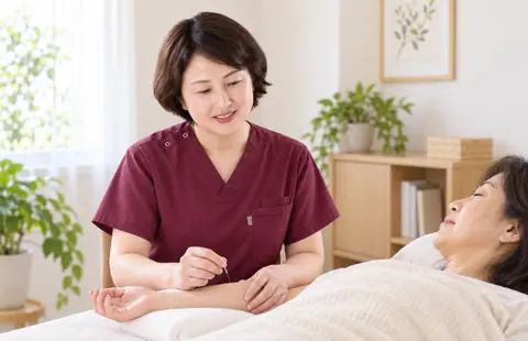 横になった女性の腕に鍼施術を行うイメージ